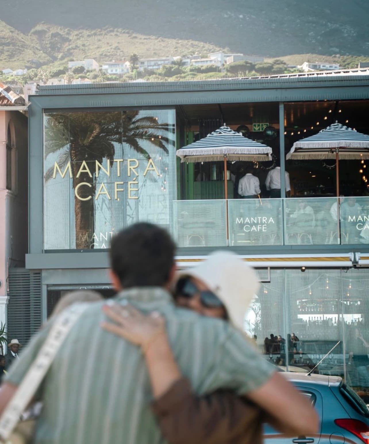 Couple looking up at the Mantra Café façade with Lion's Head behind