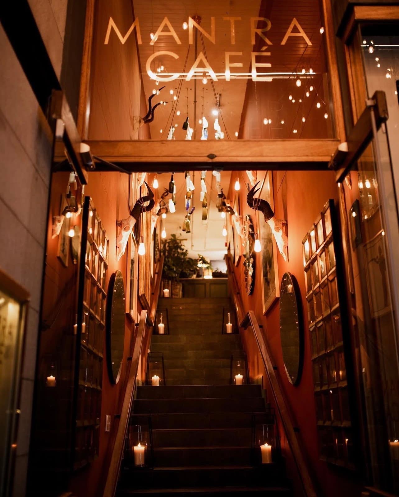 Candle-lit staircase entrance under the Mantra Café neon sign