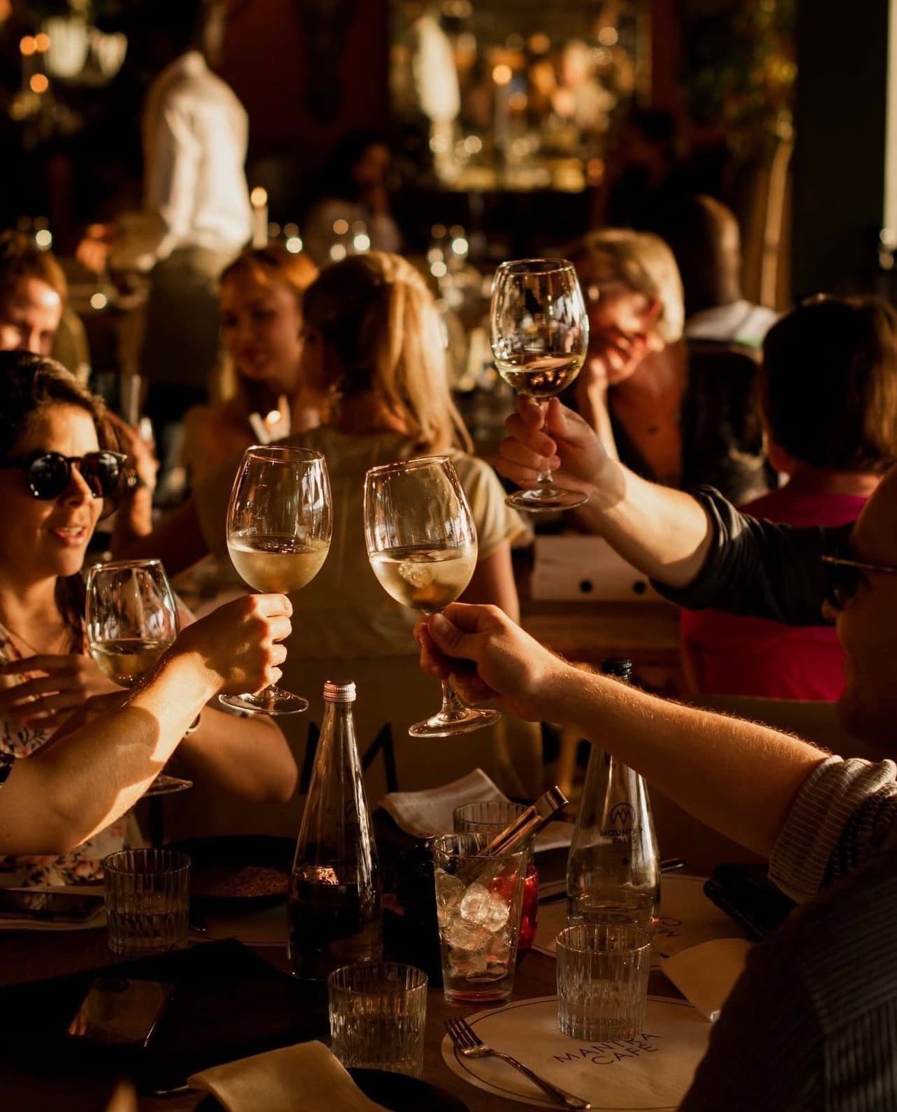 A table of friends raising white wine in a golden-hour toast