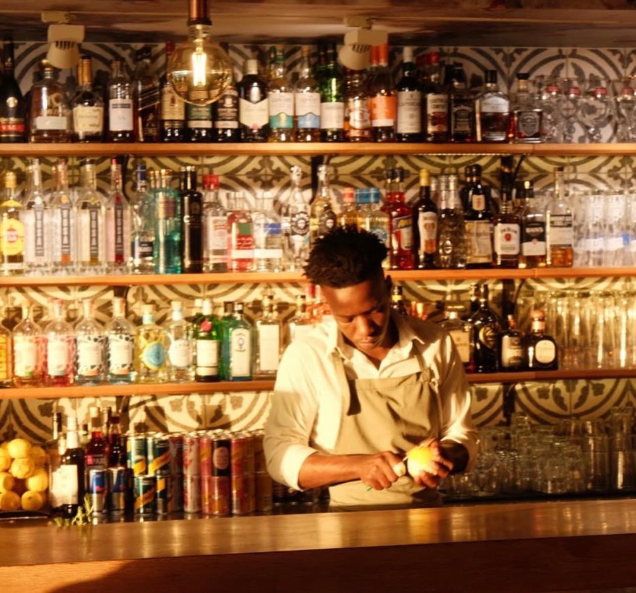A bartender at work behind the patterned-tile back-bar