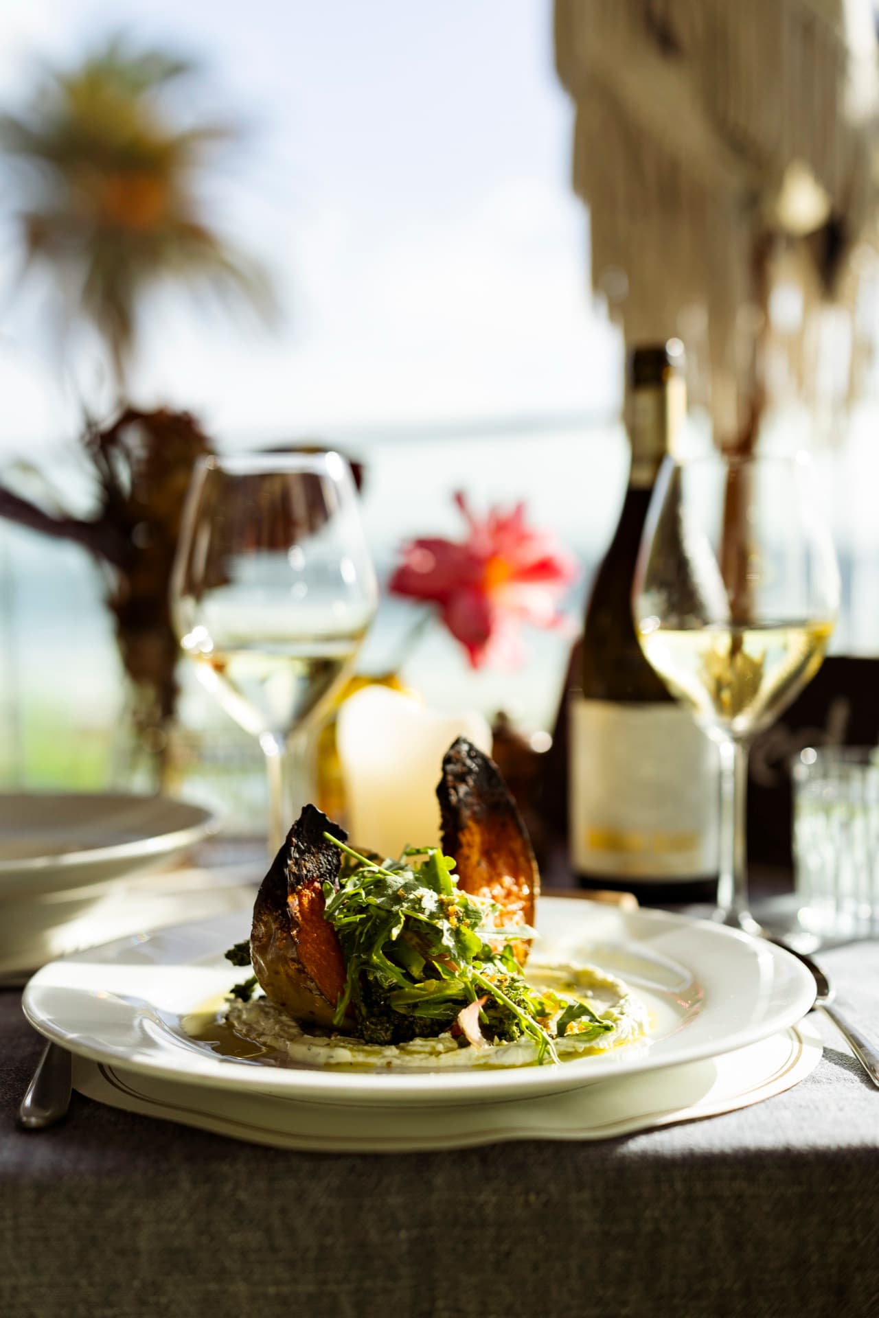 Ember-roasted pumpkin from the Winter Set Menu, framed by a palm and the Atlantic