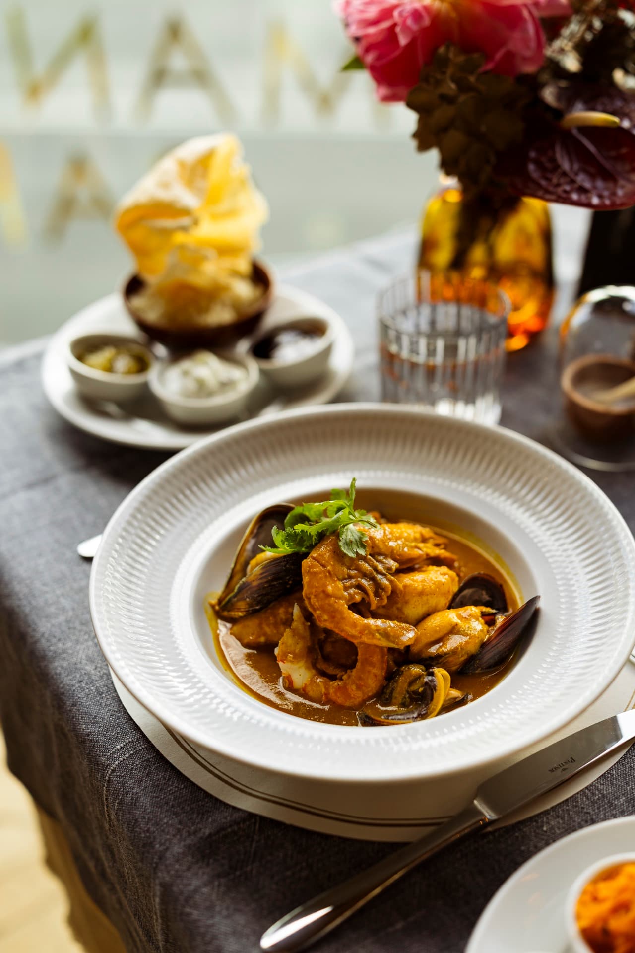 Seafood curry with prawn, mussels and coriander under the brass MANTRA letters