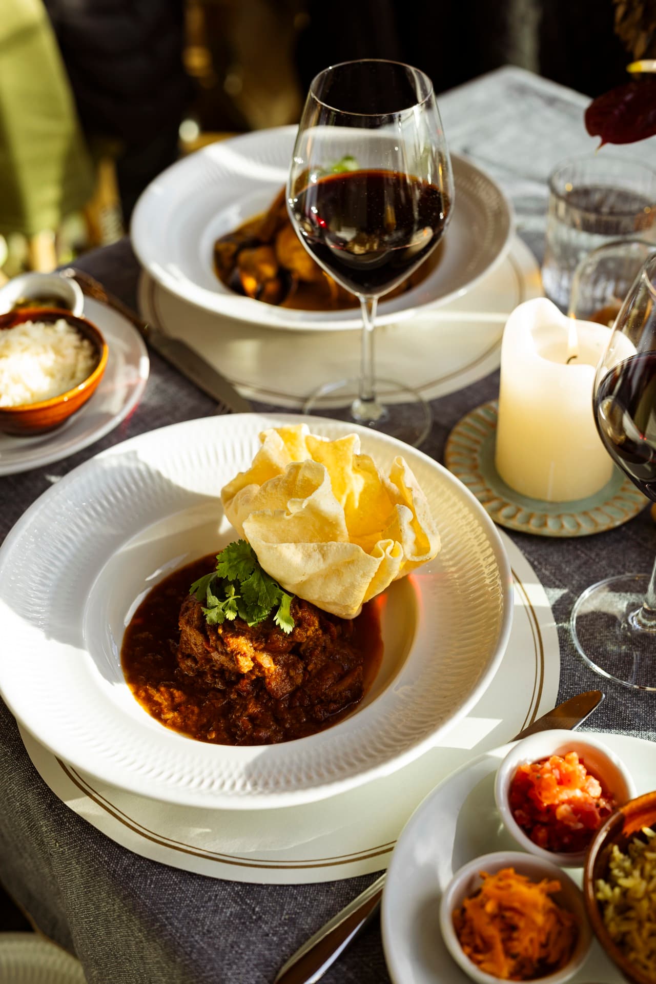 Lamb curry with poppadom and red wine — a winter table laid for two