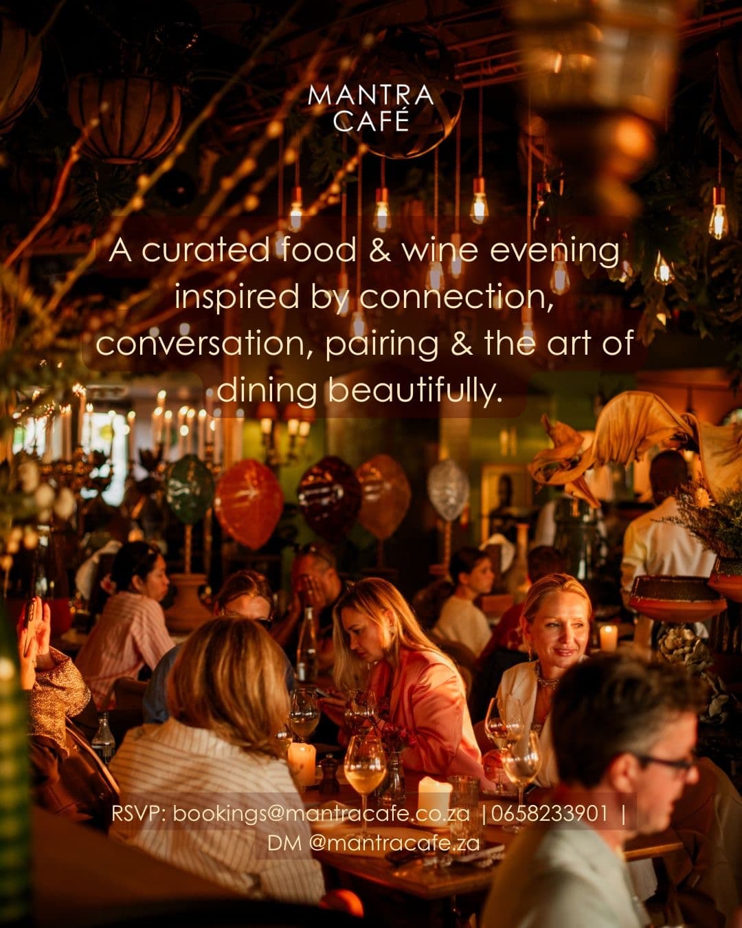 A salon evening at Mantra Café — diners gathered at candle-lit tables under hanging bulbs