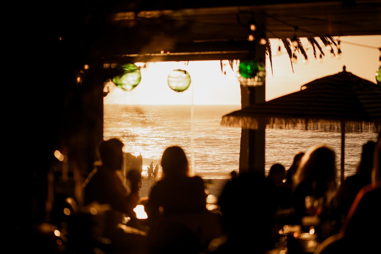 Diners em restaurante de Camps Bay com vista para o oceano no pôr do sol